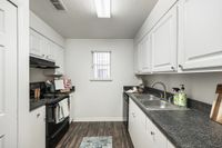 Charming galley kitchen with sleek granite countertops, modern appliances, and contemporary white cabinetry, providing a stylish and efficient cooking space.