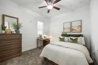 Tranquil bedroom featuring elegant wooden furniture, plush bedding with green accents, and serene artwork creating a cozy retreat.