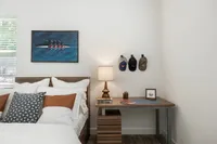 Charming bedroom with modern decor, featuring a cozy bed with stylish pillows, elegant wall art, and a sleek desk with a warm lamp.