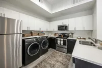 Modern kitchen showcasing sleek stainless steel appliances, a convenient washer and dryer, stylish cabinetry, and ample counter space.
