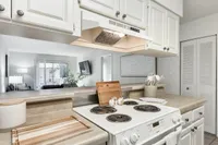 Bright and airy kitchen with sleek countertops leading to a cozy living room, featuring modern decor and abundant natural light.