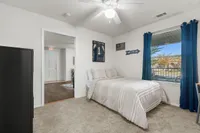 Bright and inviting bedroom with plush carpeting, elegant bed, sporty decor, and sunlit window with blue curtains.