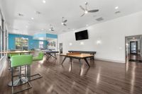 Modern community space featuring sleek wood floors, vibrant green seating, and table tennis setups for entertainment.
