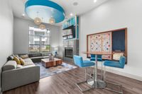 Bright and modern living room featuring elegant decor, stylish furniture, a vibrant geometric rug, and distinctive blue ceiling accents.