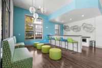 Modern communal lounge featuring vibrant blue and green seating with artistic wall decor and large windows.