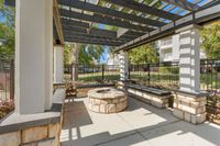 Inviting outdoor patio with pergola and cozy stone fire pit, ideal for relaxation and gatherings.