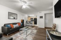 Chic open-plan apartment living room with modern black sofa, cozy colorful pillows, and sleek kitchen bar area.