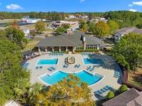 Elegant aerial view of a luxurious apartment complex featuring multiple turquoise swimming pools, surrounded by lush greenery and sun loungers, with residential buildings and vibrant landscaping in the background.