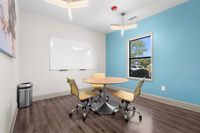 Bright and inviting meeting room with modern chairs surrounding a round table, featuring a blue accent wall and large window for natural light.