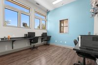Modern office space with sleek workstations, stylish wood flooring, and ample natural light through large windows.