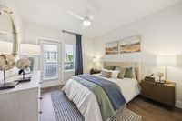 Inviting bedroom with elegant decor, featuring a cozy bed with green accents, modern artwork, and abundant natural light from large windows.