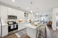 Inviting modern kitchen with sleek white cabinetry, a stylish breakfast bar, and open living area filled with natural light.