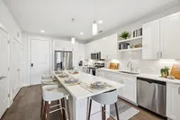 Modern and elegant kitchen with a spacious island, sleek white cabinetry, stainless steel appliances, and stylish bar seating.