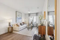 Elegant living room with modern decor, featuring a plush sofa, stylish art piece, and a chic coffee table with a bright atmosphere.