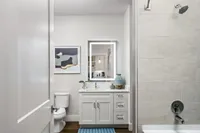 Modern bathroom featuring sleek white cabinetry, elegant wall art, and a luminous mirror, exuding contemporary style.