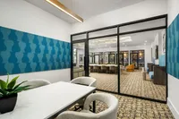 Modern office space with stylish blue acoustic panels, elegant conference table, and cozy seating in an open and inviting environment.