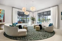 Modern lounge with chic curved sofas, geometric pendant lights, and large windows showcasing a vibrant outdoor view.