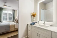Bright and modern bedroom with elegant furnishings and a pristine bathroom vanity.
