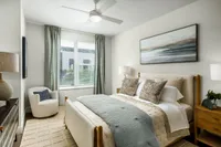 Elegant and serene bedroom with plush bedding, modern fan, and calming artwork, offering a cozy retreat.
