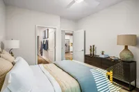 Inviting bedroom with elegant decor, soft lighting, and a view of the modern kitchen through open doors, highlighting a stylish and cohesive apartment design.