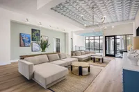 Luxurious living room with chic beige sofas, stylish patterned ceiling, and elegant decor offering a modern and inviting atmosphere.