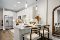 Chic modern kitchen with stainless steel appliances, sleek countertops, and elegant pendant lighting enhancing a cozy breakfast bar.