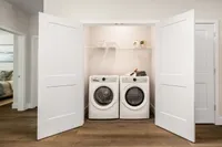 Modern laundry nook with sleek washer and dryer, featuring ample shelving in a pristine and organized space.