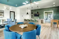 Modern apartment interior with vibrant blue and green color accents, featuring a stylish dining area, cozy seating, and open kitchen.