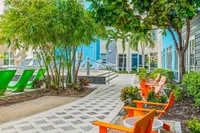 Vibrant courtyard with tropical greenery, colorful lounge chairs, and a relaxing atmosphere, perfect for outdoor enjoyment.