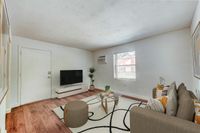 Bright and inviting living room with modern furnishings, featuring a cozy sofa, stylish glass coffee table, and sleek TV setup on beautiful hardwood floors.