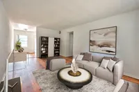 Chic living space featuring a modern sofa, artistic centerpiece table, and elegant wall art with a cozy reading nook in an open-concept design.