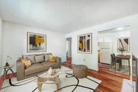 Inviting living space with modern art, cozy brown sofa, and open layout to a chic kitchen area. Perfect blend of style and comfort.