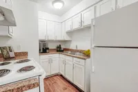 Charming kitchen with modern white cabinetry, sleek countertops, and cozy wood flooring for a welcoming atmosphere.