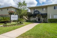 Inviting entrance to Frederick Gardens featuring lush landscaping, a welcoming path, and a stylish leasing office under a modern awning.