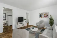 Modern living room with chic decor, featuring a cozy sofa, stylish armchairs, and a sleek TV setup, adjacent to a quaint dining area.