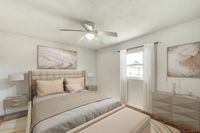 Bright and elegant bedroom featuring a plush bed with neutral-toned linens, chic bedside tables with lamps, and modern abstract artwork. Natural light floods through a large window with sheer curtains, creating a serene and inviting atmosphere.