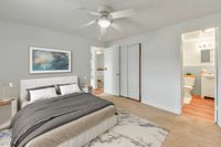 Bright and inviting bedroom with elegant decor, plush bedding, modern ceiling fan, and en-suite bathroom access.