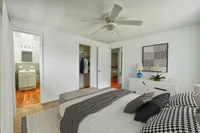 Cozy bedroom featuring a plush bed with stylish pillows, modern ceiling fan, and access to an elegant bathroom and walk-in closet.