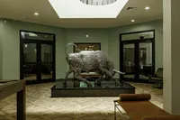 Elegant lobby with a striking metallic bull sculpture, modern design, and warm flooring, creating an inviting ambiance.