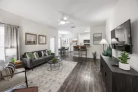 Welcoming open-concept living room with modern decor, cozy seating, and a stylish kitchen in the background.