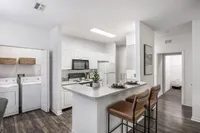 Modern apartment kitchen with sleek countertops, stylish bar seating, and in-unit laundry for convenience.