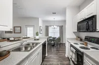 Contemporary apartment kitchen with sleek white cabinetry, spacious countertop, and adjoining dining area featuring elegant decor.