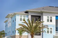 Charming coastal apartment building with sky-blue siding, modern architecture, and tropical palm trees.