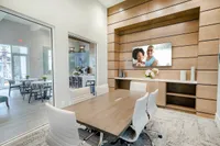 Elegant modern meeting room with sleek wooden table, plush white chairs, large windows, and stylish decor.