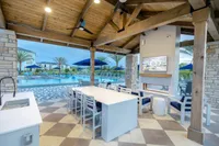 Luxurious outdoor lounge with modern furnishings, sleek fireplace, and inviting pool view framed by elegant wooden beams and stone accents.