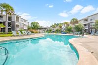 Luxury apartment complex with a pristine outdoor pool, surrounded by lush greenery and modern sun loungers, offering a serene retreat.