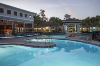 Luxurious resort-style pool area at dusk with comfortable lounge chairs, surrounded by elegant architecture and palm trees, perfect for relaxation.