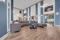 Elegant apartment lounge area featuring modern gray sectional sofas, sleek wood flooring, and stylish hanging light fixtures.