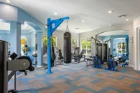 Modern fitness center with state-of-the-art equipment, vibrant blue accents, and natural light from large windows.