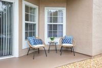 Charming patio with cozy wicker chairs, blue pattern cushions, and a sleek black table, perfect for relaxation and outdoor enjoyment.